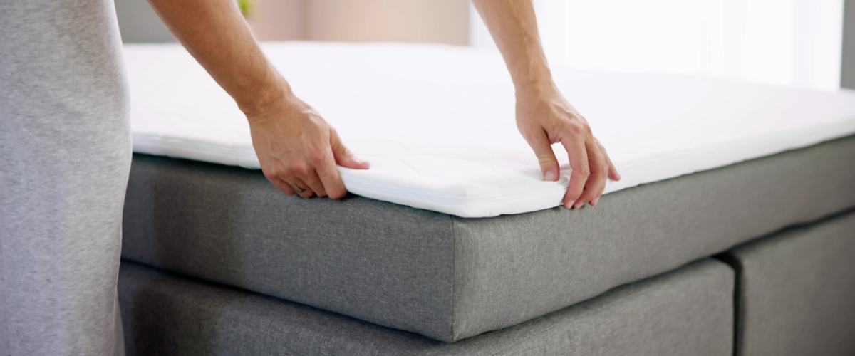 Man legt topmatras op het bed
