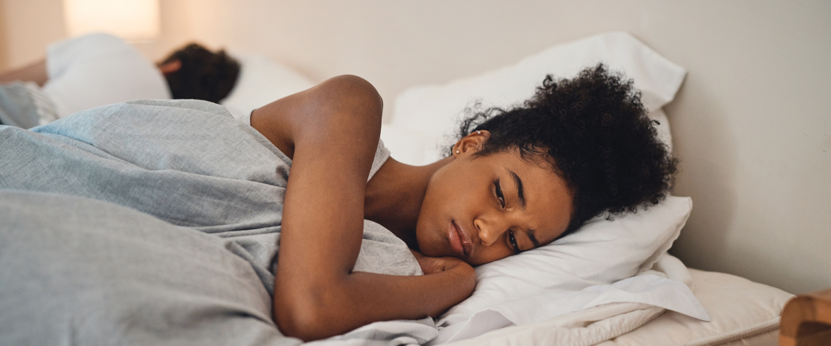 Vrouw ligt geïrriteerd wakker in bed