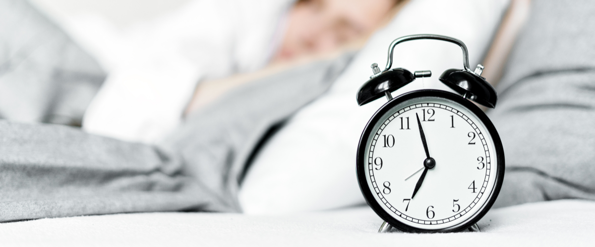 Vrouw ligt in bed en de wekker gaat af