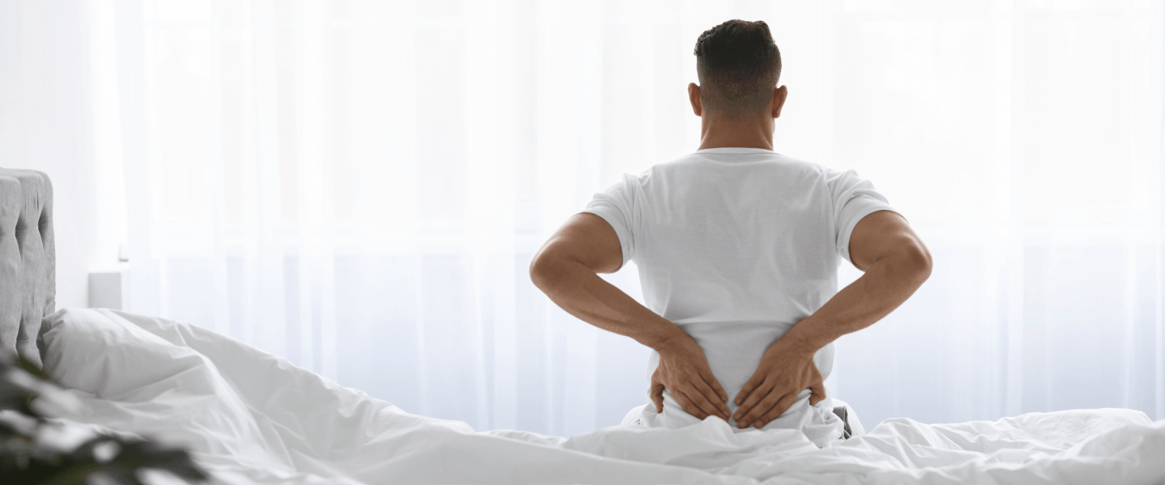 Man zit op zijn bed met rugpijn