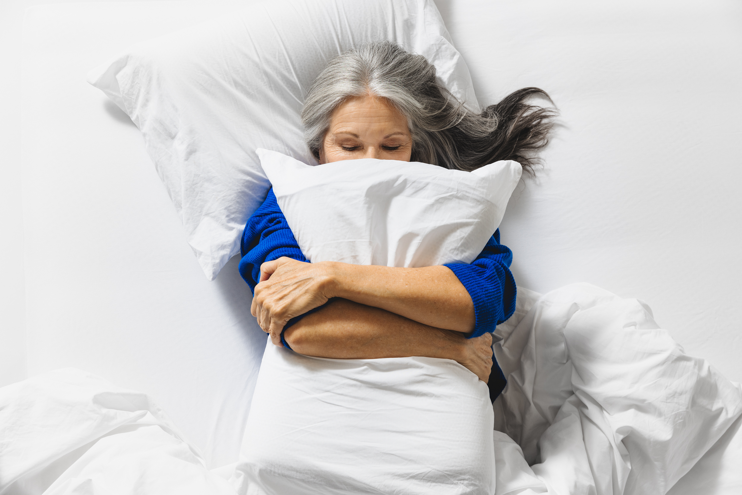 Vrouw houdt een Ergosleep kussen in haar handen en ligt heerlijk.