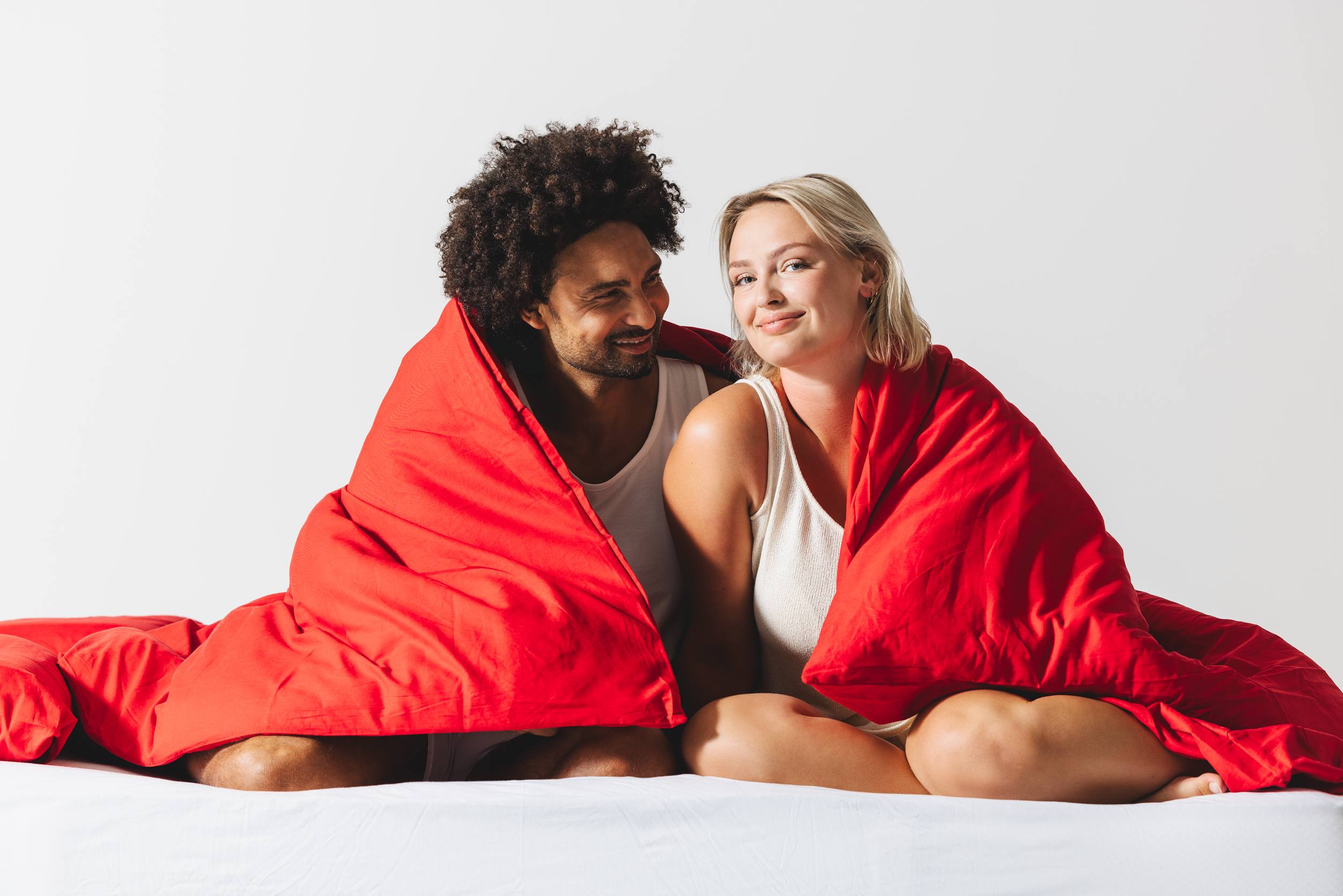 Een man en een vrouw die glimlachend naar elkaar kijken.