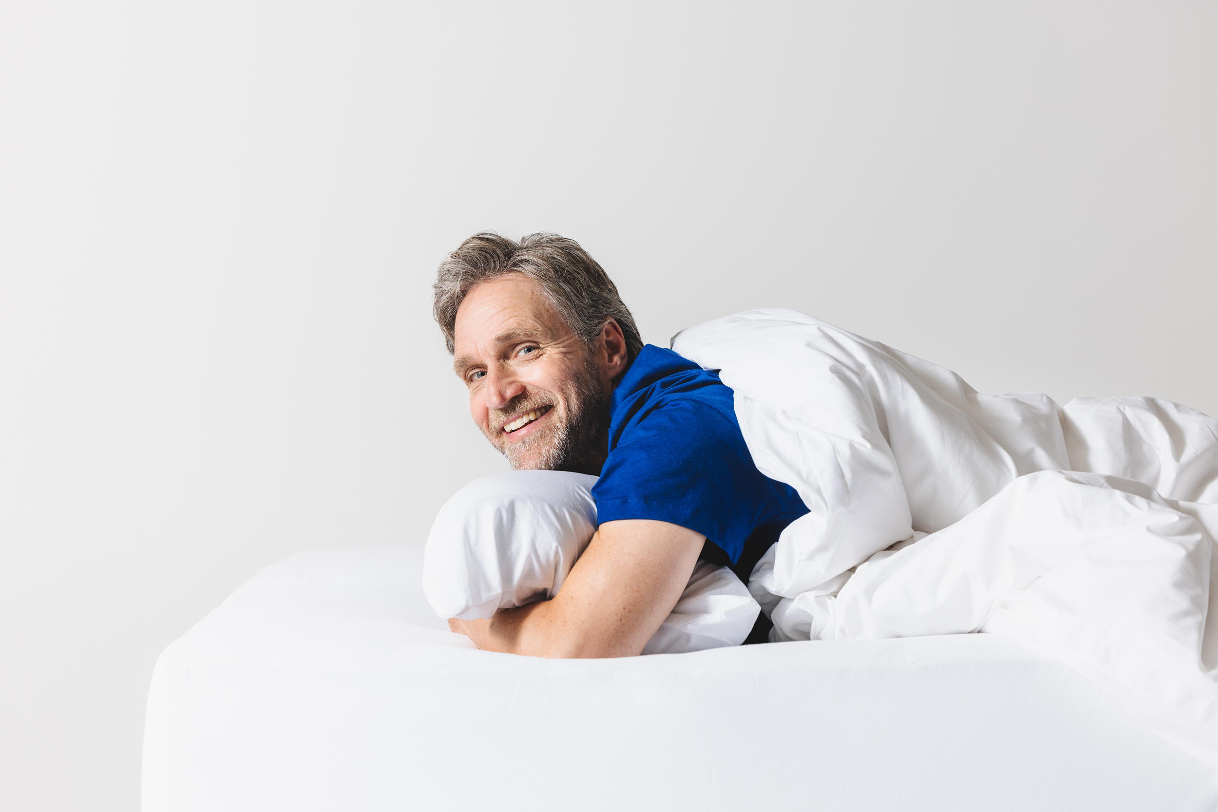 Man ligt glimlachend in bed