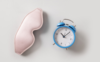 Een roze slaapmasker met een blauwe wekker